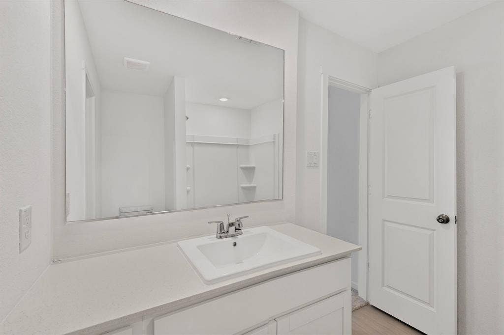 624 Kinglet Lane, Princeton, TX 75407 Bathroom featuring a rectangular undermount sink, dual-handle chrome faucet, light-toned countertop, and a large wall-mounted mirror