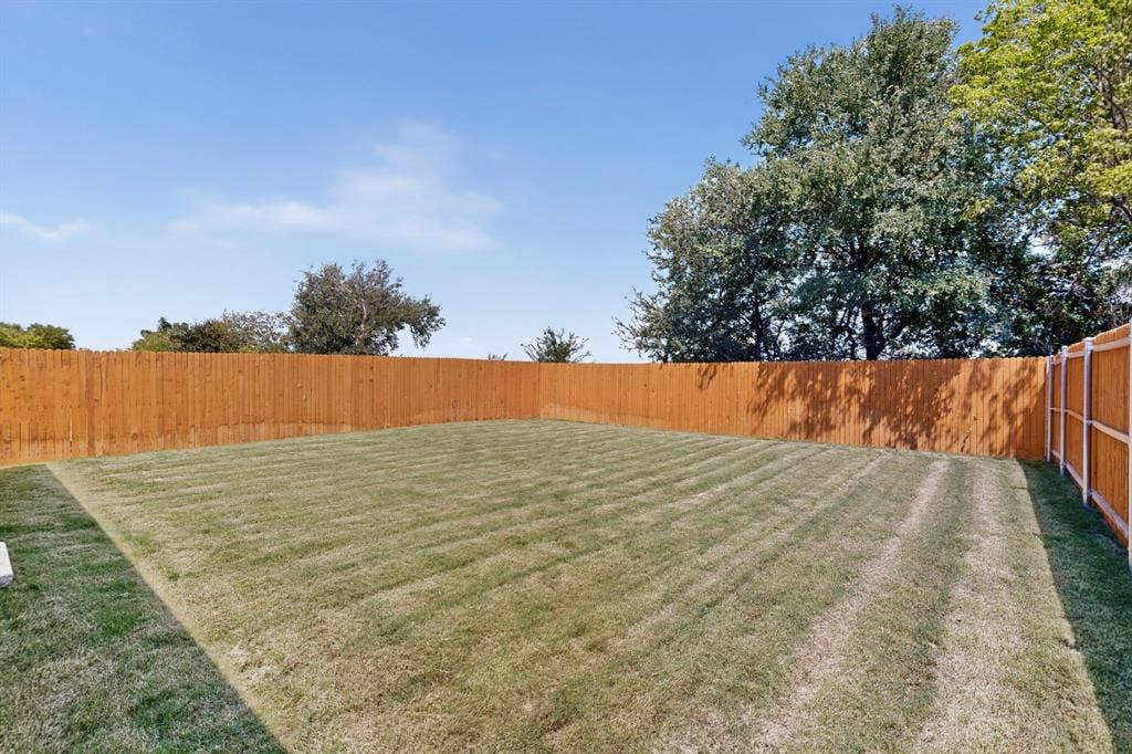 624 Kinglet Lane, Princeton, TX 75407 Expansive backyard featuring a manicured lawn, full wood fencing, and mature perimeter trees