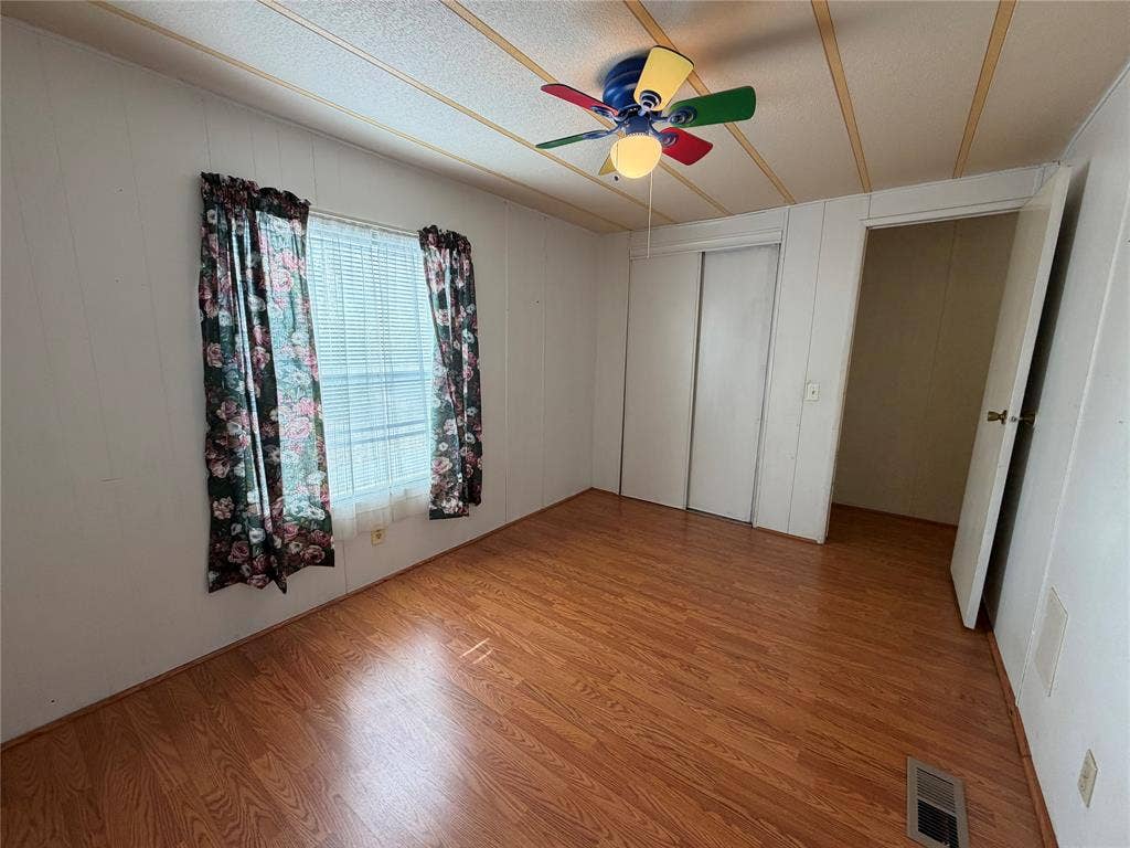 Wood-finish flooring, white walls, and a ceiling fan with integrated lighting