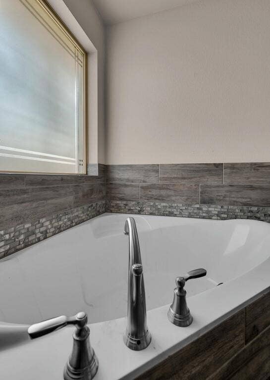 279 Sportsman Drive, Lorena, TX 76655 Soaking tub with deck-mounted chrome fixtures, complemented by wood-finish tile wainscoting and a mosaic accent band