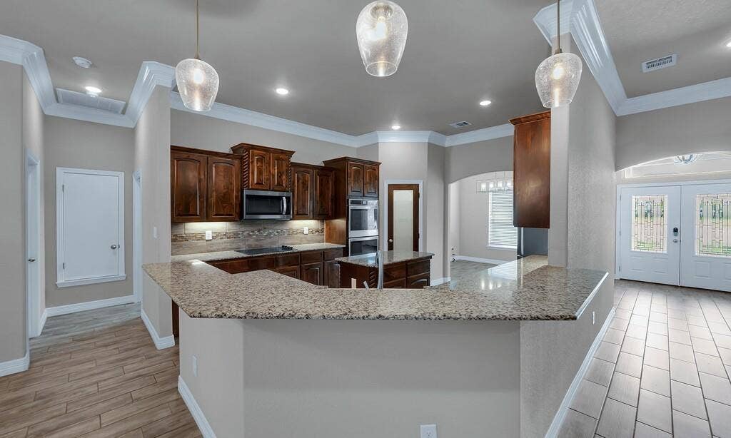 279 Sportsman Drive, Lorena, TX 76655 Kitchen with wood-finish cabinetry, built-in stainless steel appliances, and a breakfast bar with stone countertops