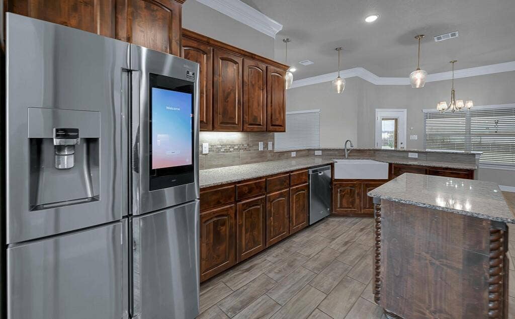 279 Sportsman Drive, Lorena, TX 76655 Kitchen featuring wood-finish cabinetry, stone countertops, a large farmhouse sink, a stainless steel refrigerator, and wood-look tile flooring