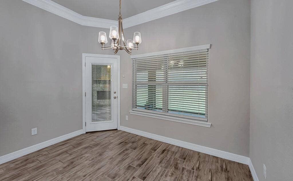 279 Sportsman Drive, Lorena, TX 76655 Wood-finish tile flooring, crown molding, a modern chandelier, a glass-paned door, and a large window with blinds