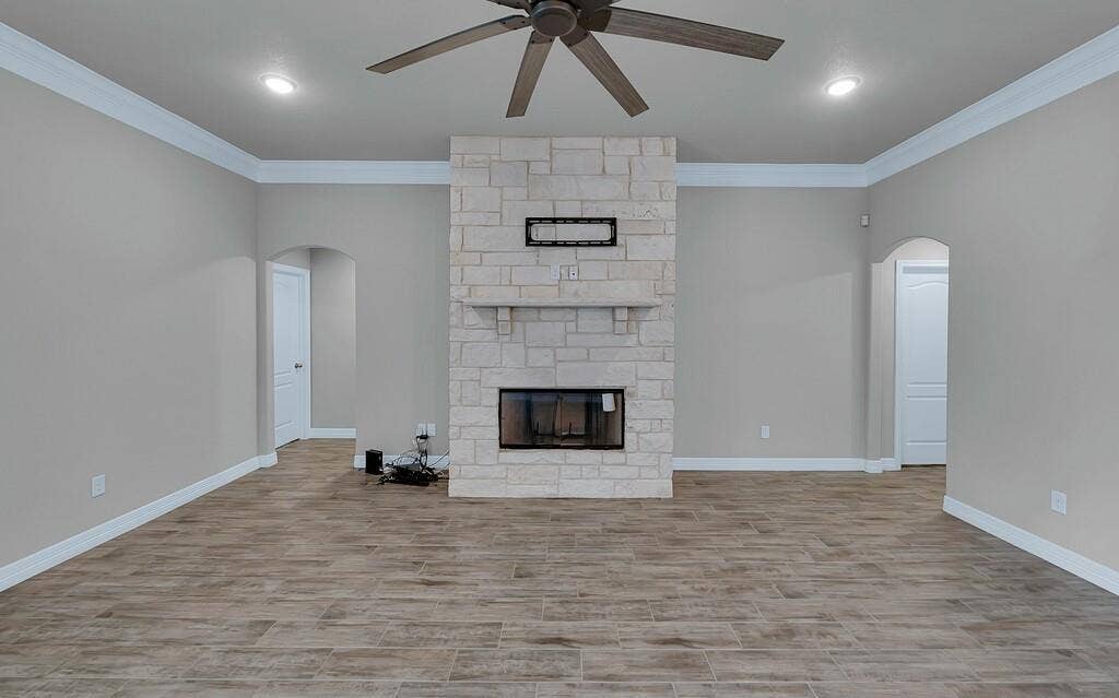 279 Sportsman Drive, Lorena, TX 76655 Stone fireplace with a hearth, wood-finish flooring, ceiling fan, recessed lighting, and arched doorways