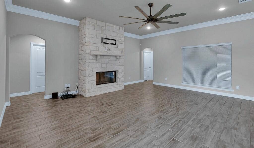 279 Sportsman Drive, Lorena, TX 76655 Spacious interior featuring wood-finish flooring, a stone-clad fireplace, and a ceiling fan with integrated lighting