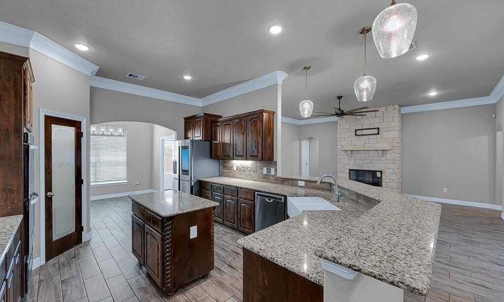 279 Sportsman Drive, Lorena, TX 76655 Kitchen featuring an island, granite countertops, dark wood cabinetry, and stainless steel appliances