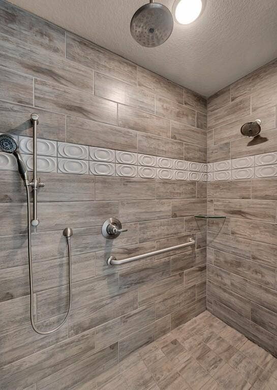 279 Sportsman Drive, Lorena, TX 76655 Walk-in shower featuring wood-look tile, decorative accent tile, a rain showerhead, and a handheld shower attachment