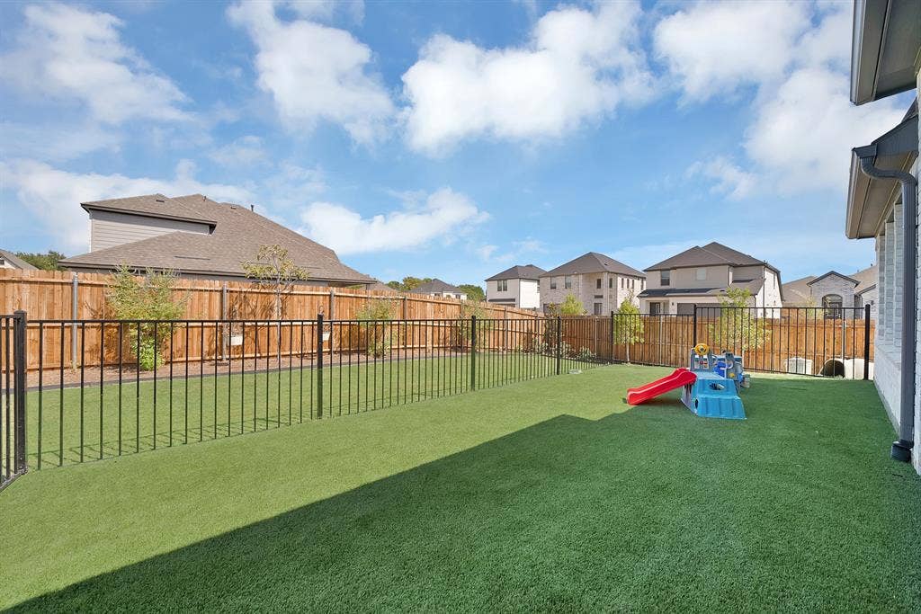 3701 Turpin Drive, Princeton, TX 75071 Expansive backyard with professionally installed synthetic turf, black wrought iron perimeter fencing, and dedicated play area.