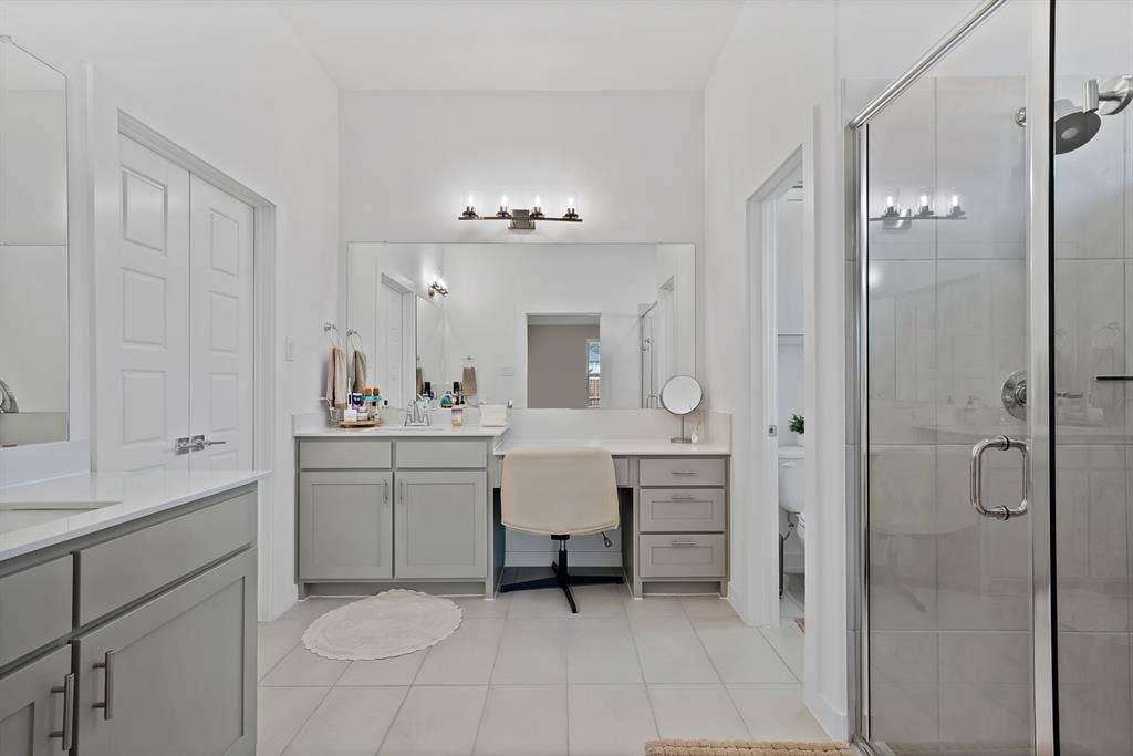 3701 Turpin Drive, Princeton, TX 75071 Dual vanity with white countertops and light gray cabinetry, glass-enclosed shower, tiled flooring, and a dedicated vanity seating area.