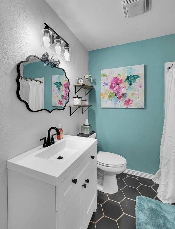 3720 Trice Avenue, Waco, TX 76707 White vanity with an integrated sink and matte black faucet, hexagonal floor tiles, and a three-light vanity fixture