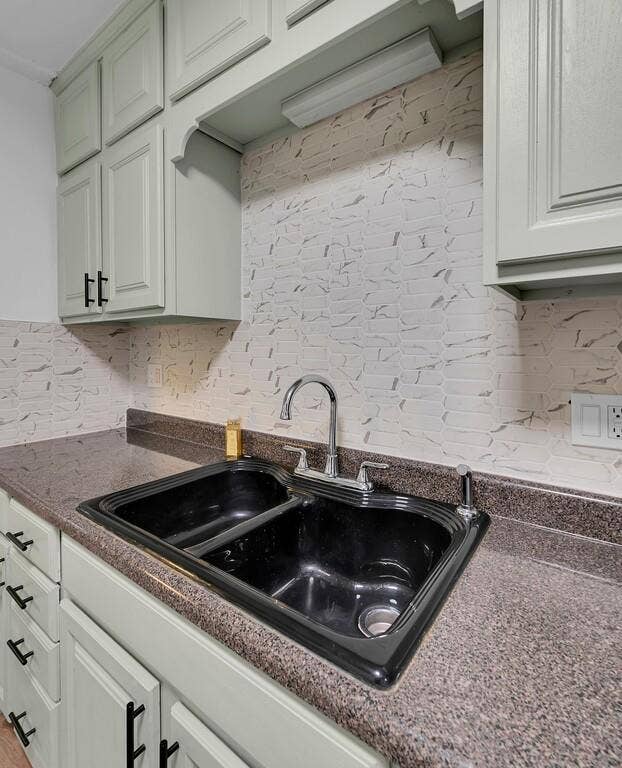 3720 Trice Avenue, Waco, TX 76707 Light-toned cabinetry with modern black hardware, dual basin sink, chrome faucet, and textured tile backsplash