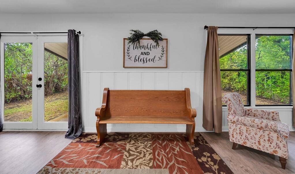 3720 Trice Avenue, Waco, TX 76707 White wainscoting accenting light-toned walls, wood-finish flooring, and a double French door with black hardware