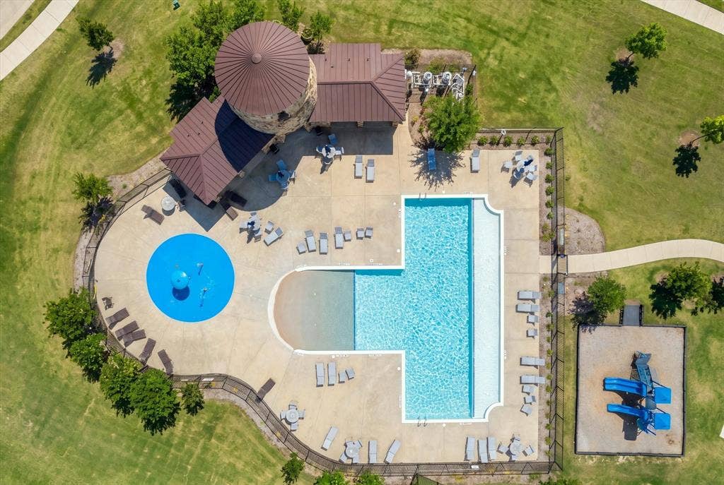 Large swimming pool with integrated shallow entry, adjacent splash pad, and playground structure