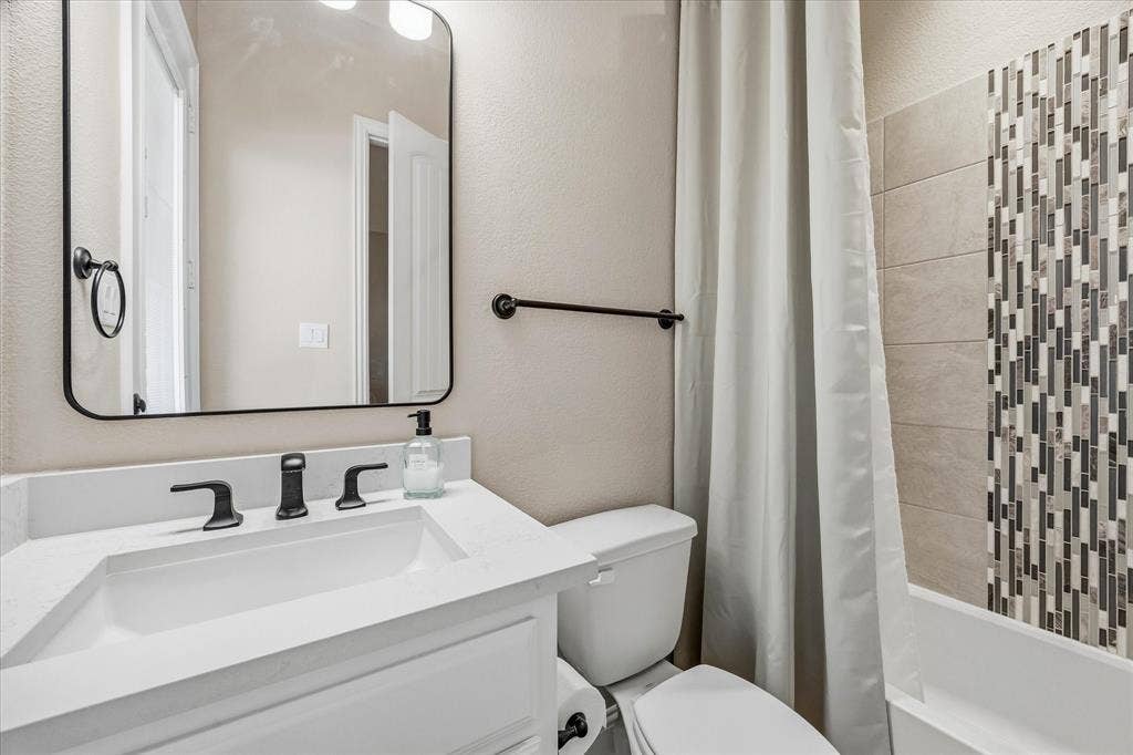 Vanity with a white countertop and rectangular sink, matte black faucet, and a framed mirror
