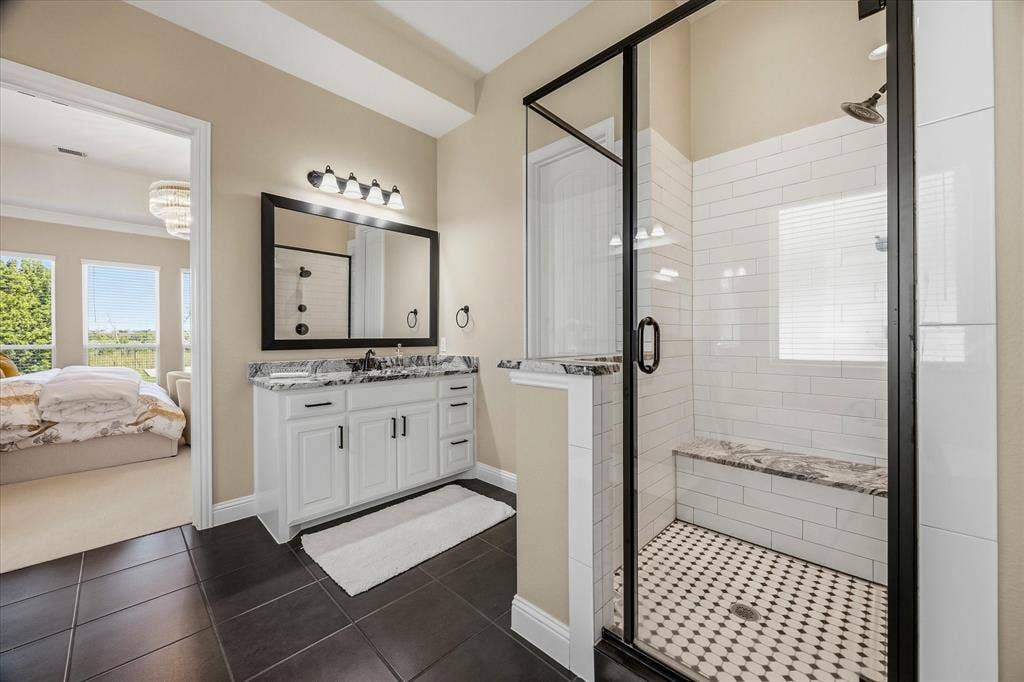 Bathroom featuring a vanity with white cabinetry and dark hardware, a dark-framed mirror, and an attached lighting fixture