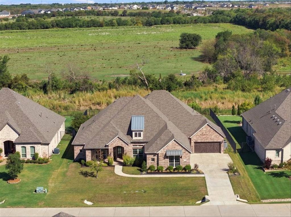 Brick exterior with stone accents, covered entry, attached garage, concrete driveway, and manicured landscaping