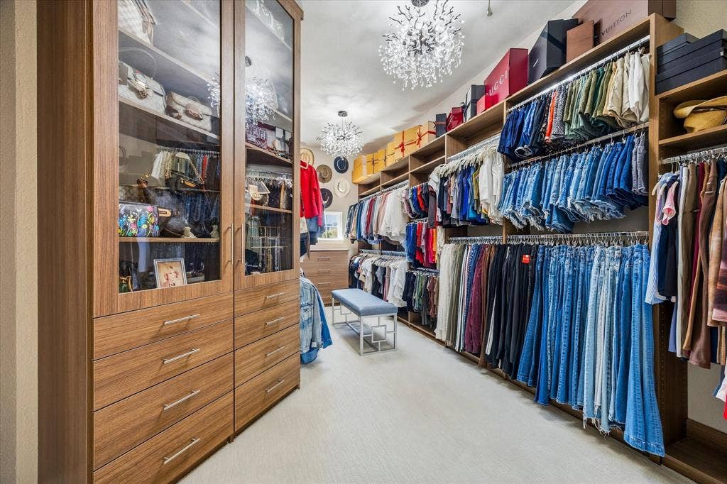 Built-in closet system featuring wood-finish cabinetry, glass-front display cabinets, and integrated drawer storage