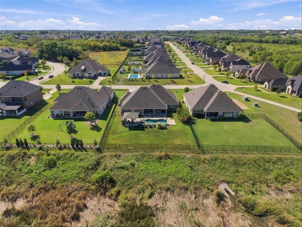 Expansive residential neighborhood with consistent home styles, dark shingle roofs, and private fenced backyards