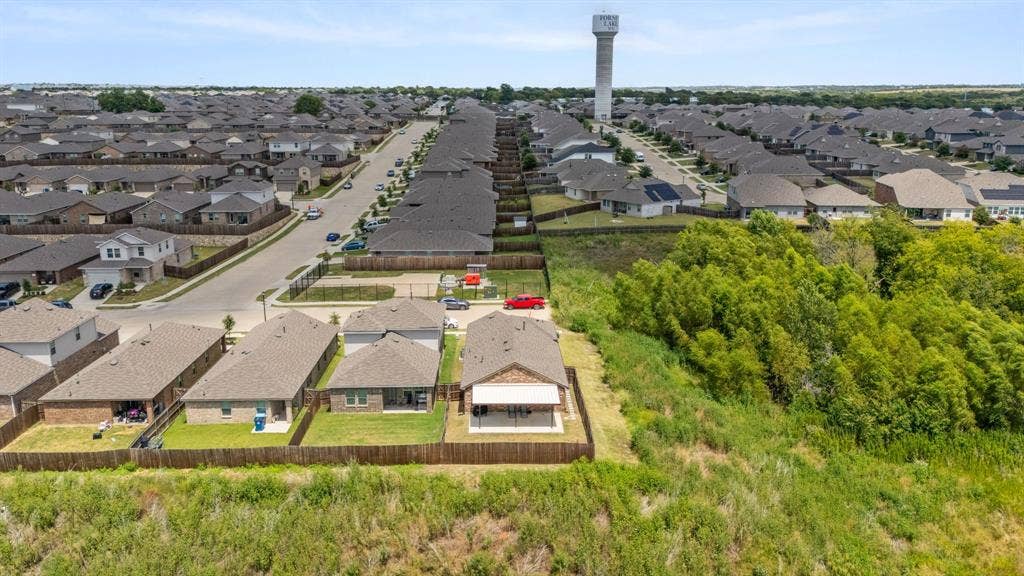 Residential community with a cohesive architectural style, individual fenced yards, and natural green space bordering the property