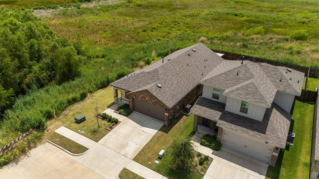Contemporary residence featuring a two-car garage, brick facade, and a shingle roof