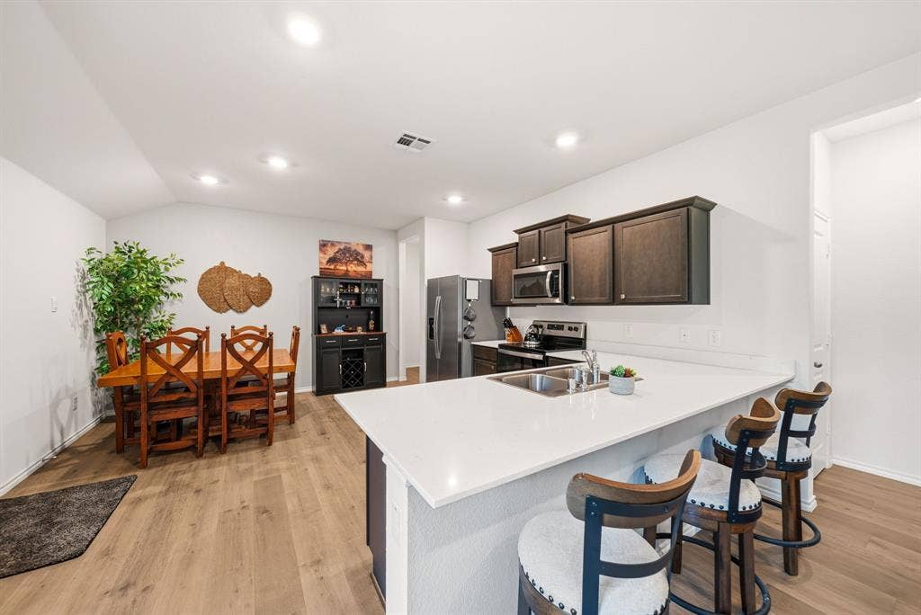 Kitchen featuring a stainless steel sink, dark wood-finish cabinetry, and a white countertop