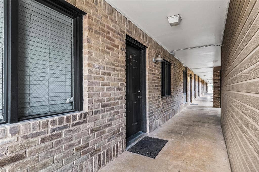 1214 Baylor Avenue, #109, Waco, TX 76706 Brick exterior facade with black window frames, sconce lighting, and a concrete walkway