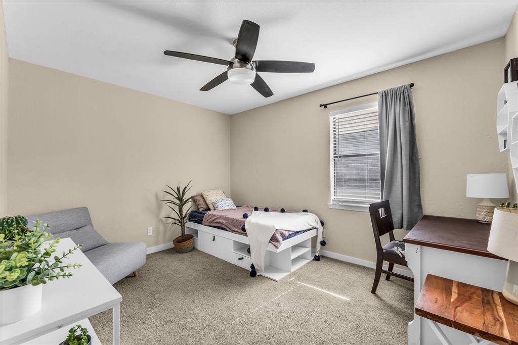 1214 Baylor Avenue, #109, Waco, TX 76706 Neutral tone wall paint, carpet flooring, window with blinds, ceiling fan, and built-in storage beneath the bed frame