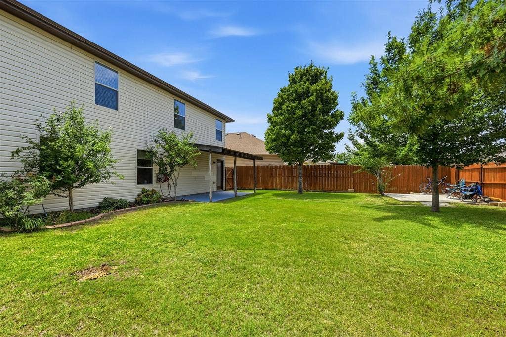 800 Poncho Lane, Fort Worth, TX 76052 Expansive backyard featuring a manicured lawn with mature shade trees and wooden privacy fencing