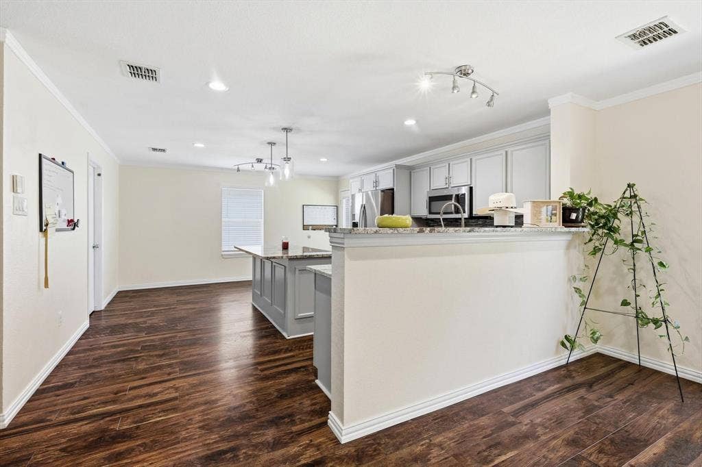 800 Poncho Lane, Fort Worth, TX 76052 Modern kitchen featuring white cabinetry with a large center island, stainless steel appliances, recessed and pendant lighting, and wood-finish flooring throughout the open-concept space