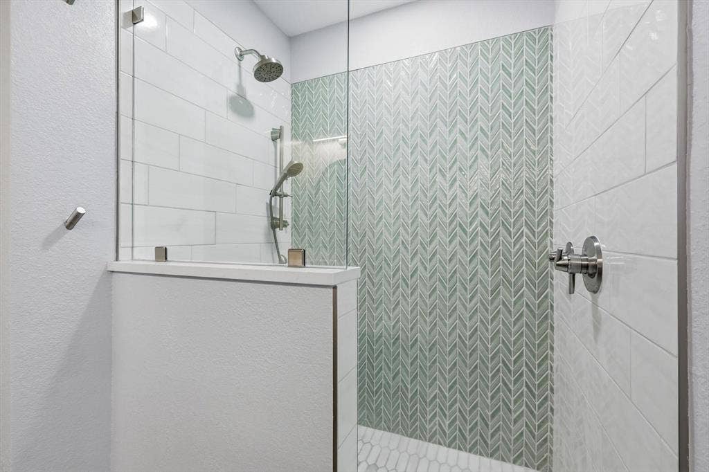 800 Poncho Lane, Fort Worth, TX 76052 Glass-enclosed shower with a rainfall showerhead, handheld sprayer, and herringbone accent tile