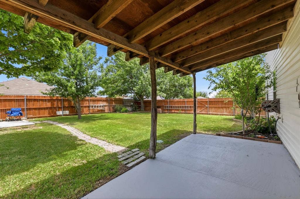 800 Poncho Lane, Fort Worth, TX 76052 Expansive backyard oasis featuring a covered patio with exposed beam construction, concrete flooring, and mature shade trees