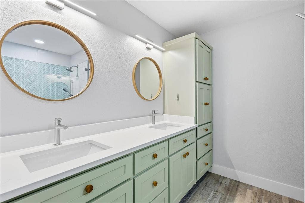 800 Poncho Lane, Fort Worth, TX 76052 Spa-inspired primary bathroom featuring dual undermount sinks with a continuous white quartz countertop, soft-close cabinetry in sage green with brass hardware, and polished chrome faucetry