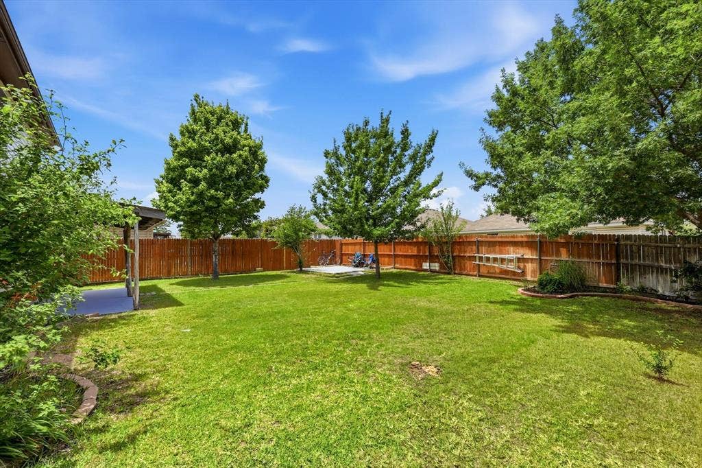 800 Poncho Lane, Fort Worth, TX 76052 Expansive backyard featuring a manicured lawn, mature shade trees, and wood-finish fencing