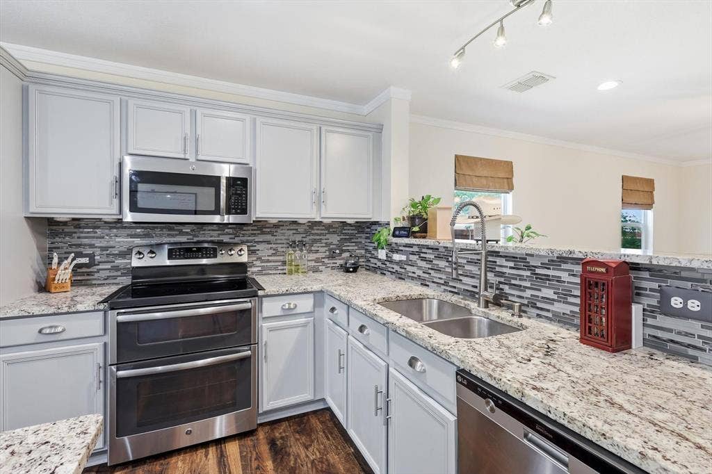 800 Poncho Lane, Fort Worth, TX 76052 Kitchen featuring granite countertops, stainless steel appliances, a tile backsplash, light-toned cabinetry, and wood-finish flooring