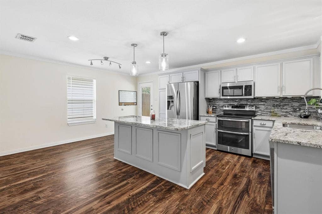 800 Poncho Lane, Fort Worth, TX 76052 Modern kitchen featuring white cabinetry with a large center island, stainless steel appliances including a double wall oven and microwave, granite countertops, and a tile backsplash