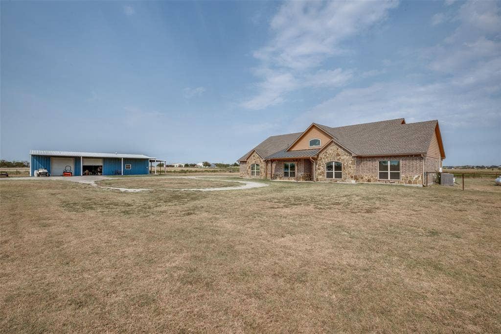 8400 Holder Road, Northlake, TX 76247 Stone and brick exterior with a pitched roof, featuring multiple windows, and an accompanying blue metal outbuilding with open bays