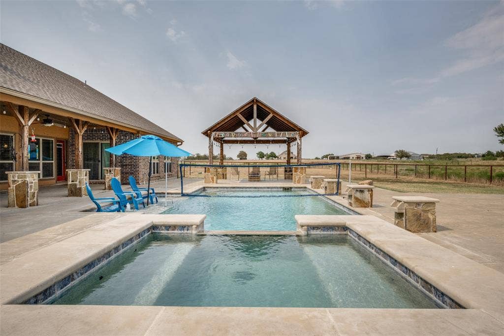 8400 Holder Road, Northlake, TX 76247 Expansive concrete patio with a built-in swimming pool and spa, featuring stone-clad water features