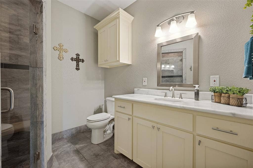 8400 Holder Road, Northlake, TX 76247 Walk-in shower with tile surround, vanity with light-colored cabinetry, polished countertop, and an integrated sink