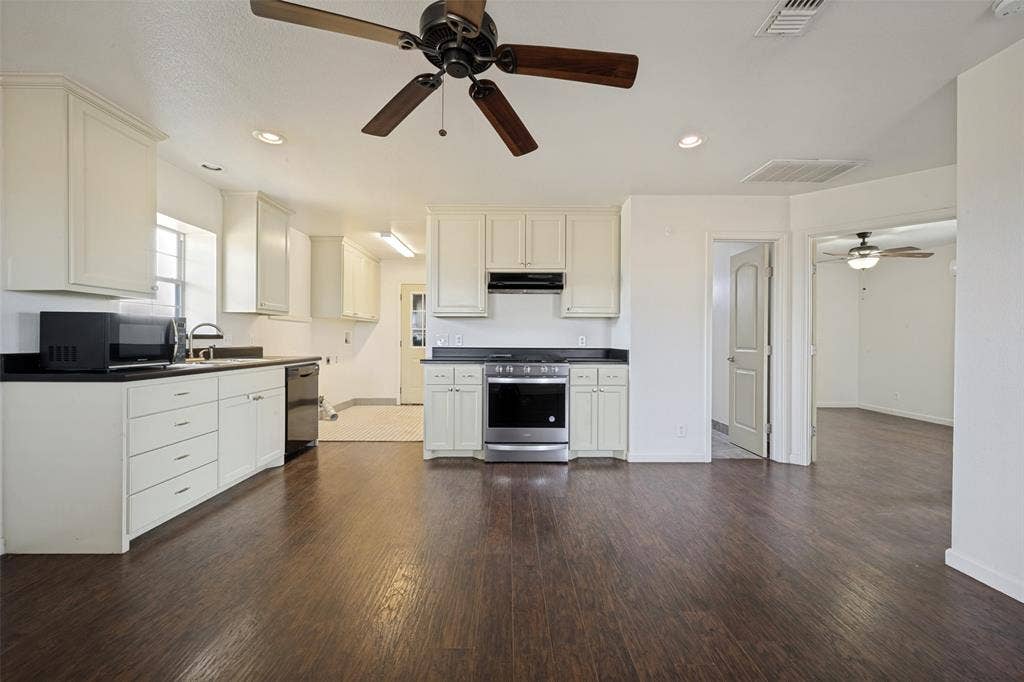 8400 Holder Road, Northlake, TX 76247 Open-concept living space with dark wood-finish flooring, white cabinetry, dark countertops, and stainless steel appliances