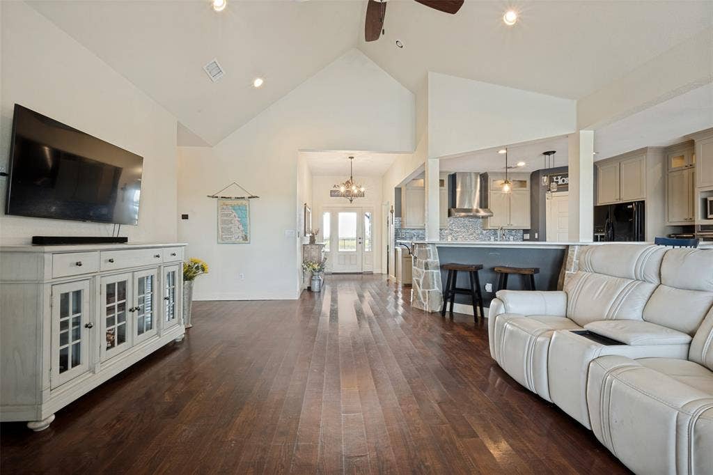 8400 Holder Road, Northlake, TX 76247 Vaulted ceilings with recessed lighting, wood-finish flooring, kitchen pass-through with stone-clad half wall, stainless steel range hood, and pendant lighting