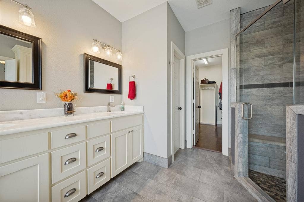 8400 Holder Road, Northlake, TX 76247 Primary bathroom with dual vanity with a white countertop and undermount sinks, framed mirrors, and chrome light fixtures
