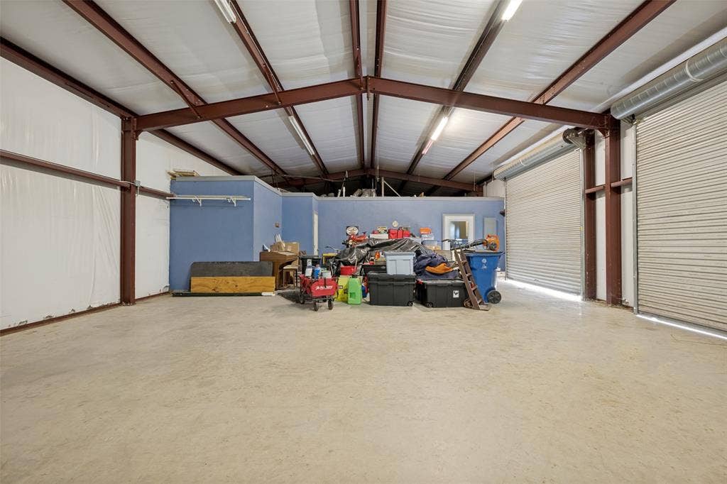 8400 Holder Road, Northlake, TX 76247 Barndo garage space interior with exposed steel beam construction, a concrete floor, and two large roll-up doors