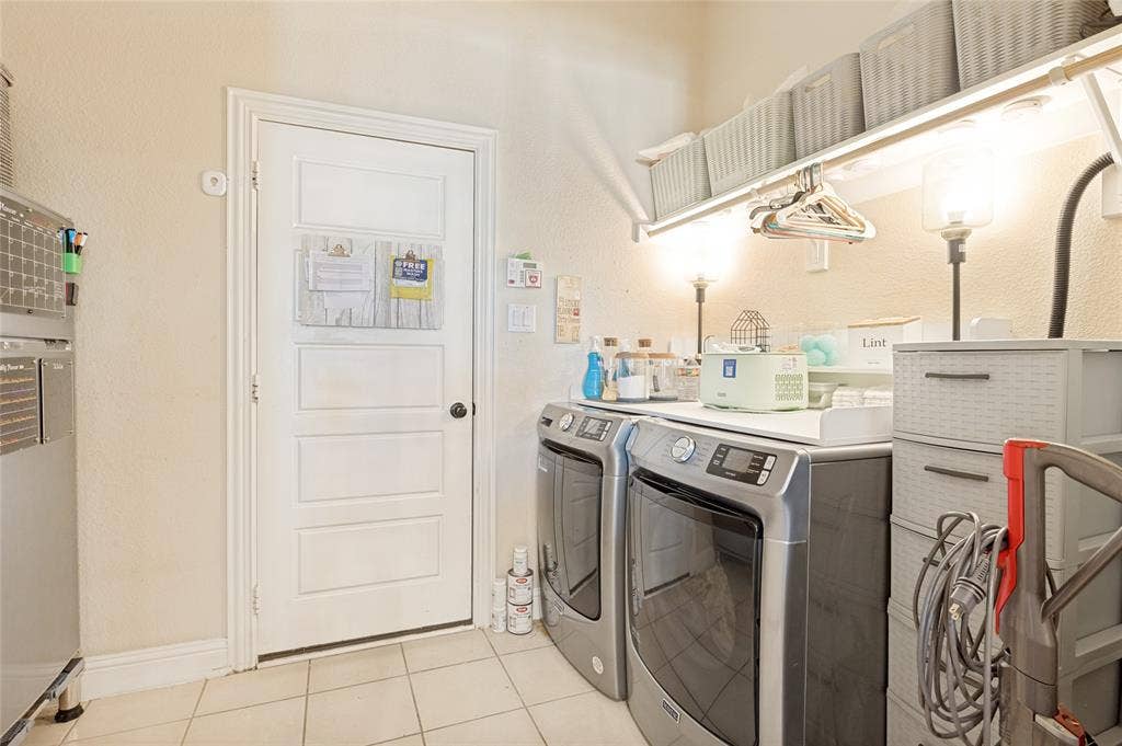 4601 Massey Meadows Way, Midlothian, TX 76065 Utility space featuring tiled flooring, a white paneled door, and built-in overhead shelving