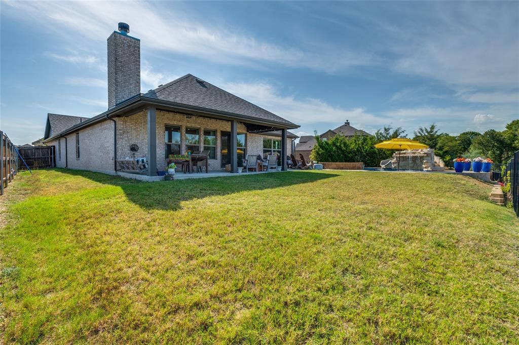 4601 Massey Meadows Way, Midlothian, TX 76065 Expansive backyard featuring a covered patio, a swimming pool with a stone waterfall, a substantial brick-clad chimney, and a durable shingle roof