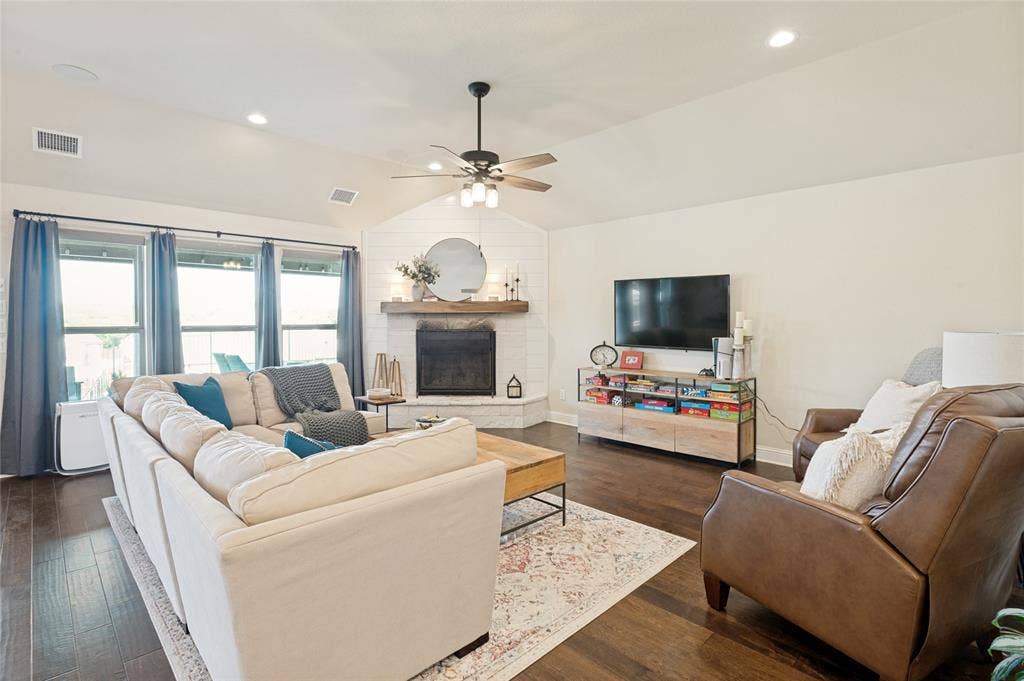 4601 Massey Meadows Way, Midlothian, TX 76065 Vaulted ceiling with a ceiling fan, fireplace with a wood mantle, white shiplap accent wall, dark wood-finish flooring, and recessed lighting