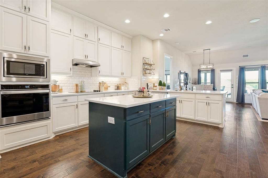 4601 Massey Meadows Way, Midlothian, TX 76065 Gourmet kitchen with wood-finish flooring, white cabinetry, subway tile backsplash, and a contrasting island