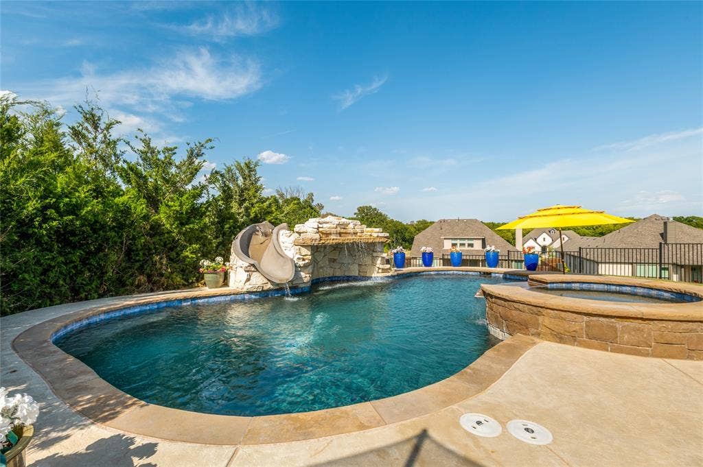 4601 Massey Meadows Way, Midlothian, TX 76065 Curved swimming pool with stone waterfall feature, integrated spa, and concrete deck