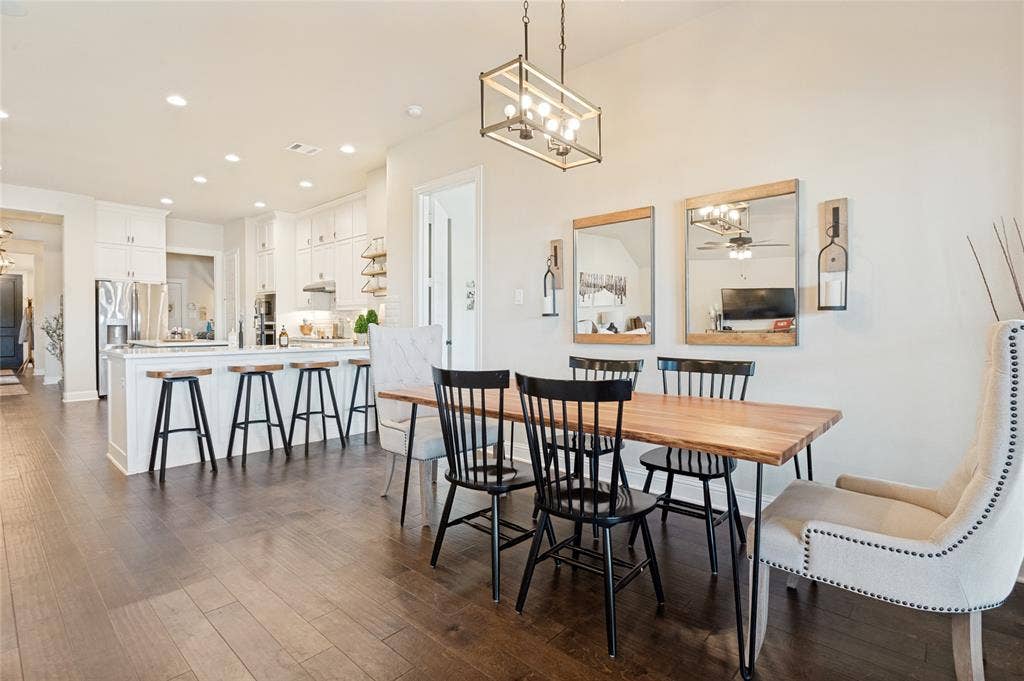 4601 Massey Meadows Way, Midlothian, TX 76065 Wood-finish flooring throughout, white kitchen cabinetry, recessed lighting, kitchen island with seating, and a dining area with a linear chandelier