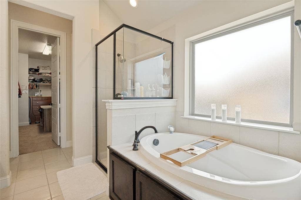 4601 Massey Meadows Way, Midlothian, TX 76065 Soaking tub with dark wood-finish paneling, an enclosed shower with black framing, and a frosted window