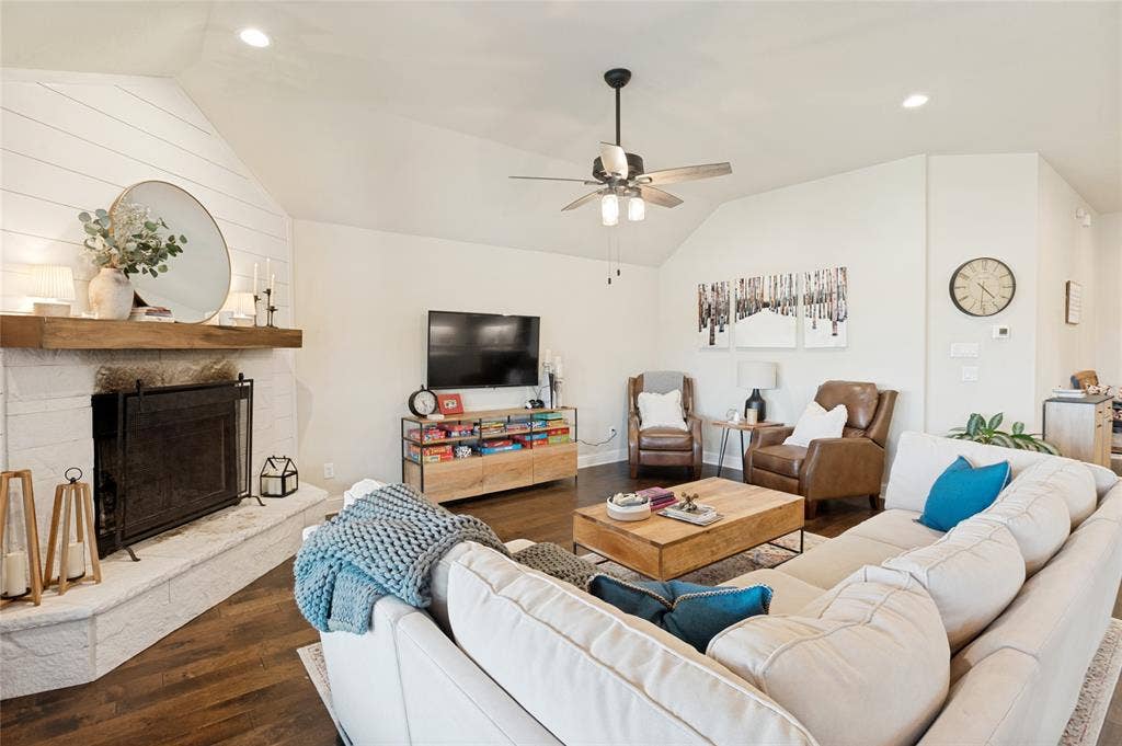4601 Massey Meadows Way, Midlothian, TX 76065 Vaulted ceiling with a ceiling fan, wood-finish flooring, white shiplap fireplace wall, painted brick fireplace surround, and a natural wood mantel